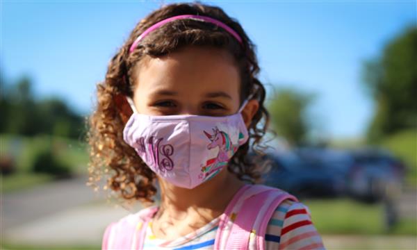 girl smiles while wearing mask